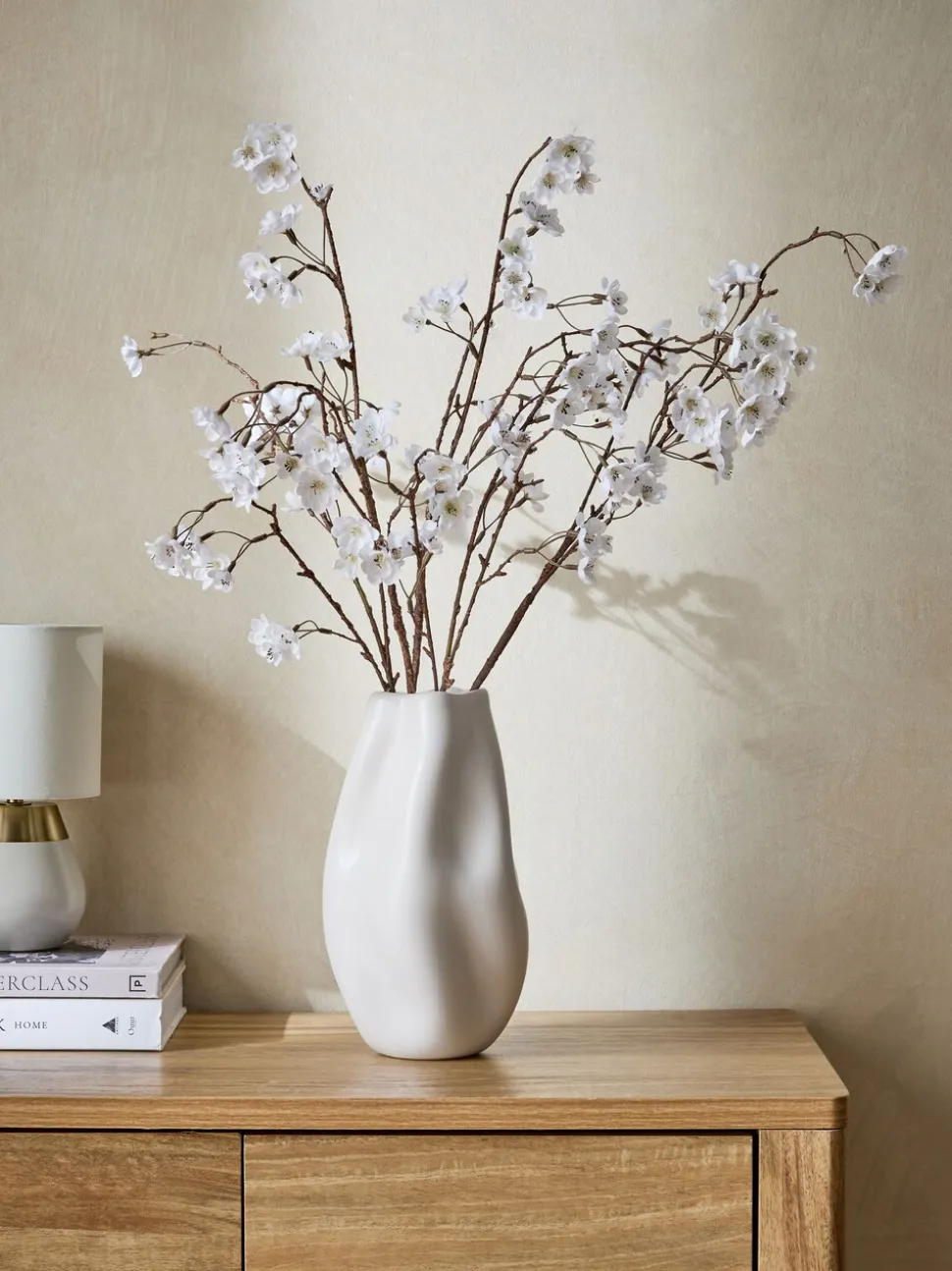Kunstbloesemstelenarrangement in witte keramische vaas